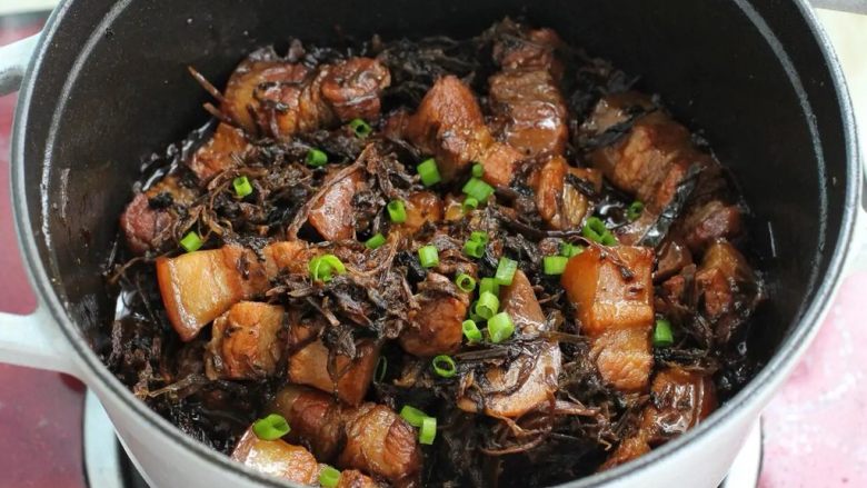 梅干菜烧肉,待肉质软烂、汤汁减少后按照个人口味调入盐,改大火翻炒收汁,撒少许葱花点缀即可。