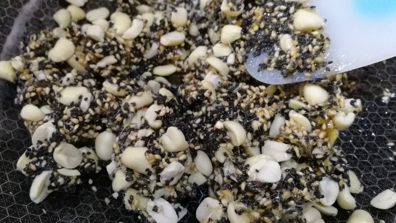 芝麻花生糖,倒入黑芝麻和白芝麻,快速翻拌均匀。