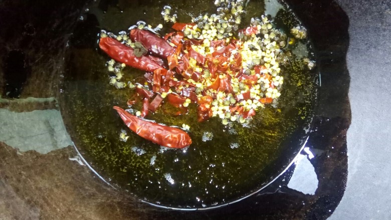 酸菜肥牛,炒锅倒菜籽油,放入干辣椒和花椒小火炒香。