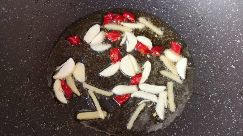 酸菜肥牛,炒锅内倒适量的食用油烧热,下入姜丝蒜片和干红辣椒炒香。