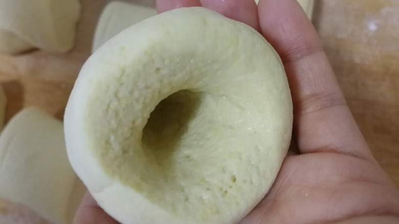 玉米面窝窝头,取一个面剂,拇指插入,其余四指包紧并旋转面剂。