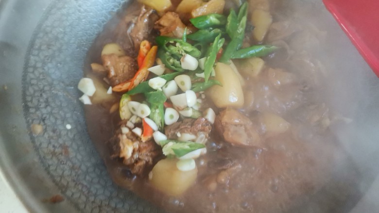 鸡肉炖土豆,待鸡肉土豆炖烂,加入尖椒和大蒜翻炒至尖椒断生