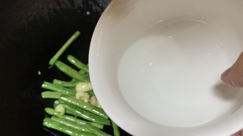 清炒四季豆,倒入2汤勺清水，翻炒1分钟