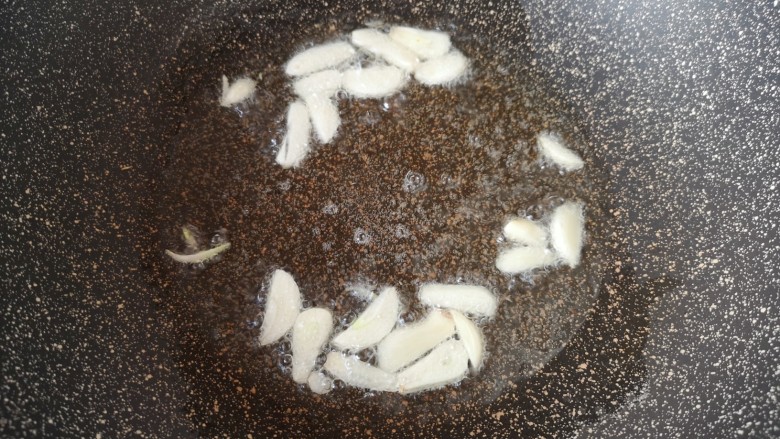清炒四季豆,炒锅内倒适量的食用油烧热,下入蒜片炒香。