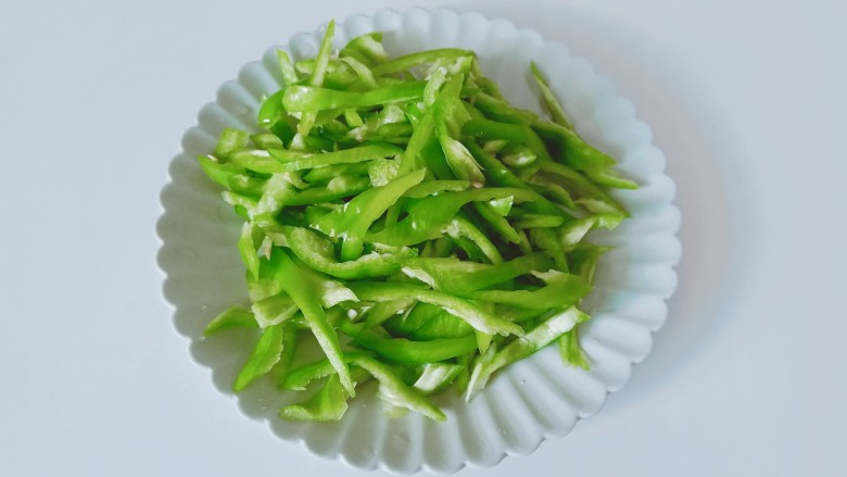尖椒牛柳,尖椒去蒂对半切开,挖出里面的籽,再切成细丝。