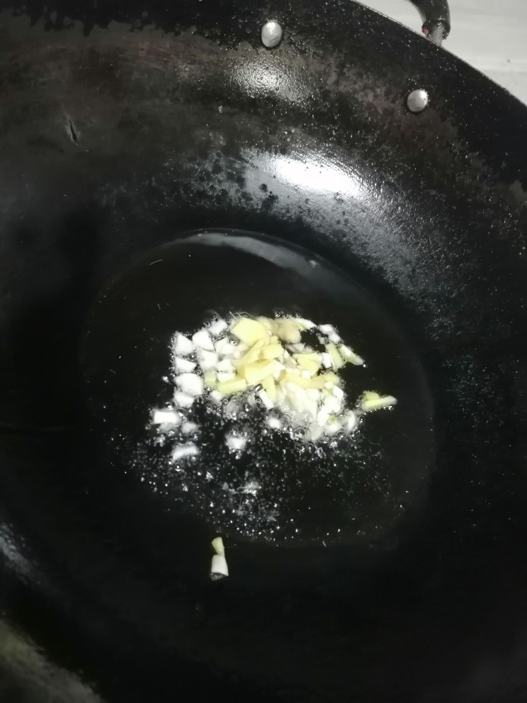 红烧米豆腐,开火加热锅倒入蒜瓣和姜炒香