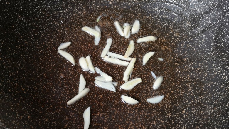 尖椒牛柳,锅里继续倒油烧热,下入蒜片炒香。