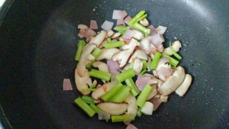 鸡蛋炒乌冬面,锅中加入适量花生油烧热,放入洋爆香,加入香菇和芹菜翻炒1分钟