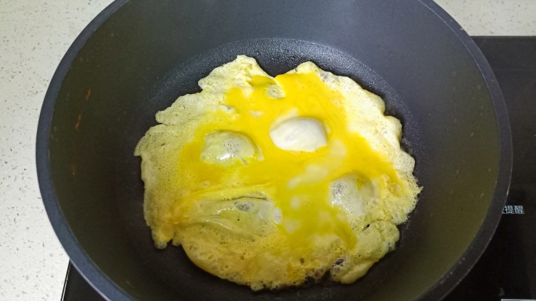 鸡 蛋炒乌冬面,锅里放适量的食用油,油热倒入鸡蛋液。用筷子快速将它们搅散,盛盘备用。