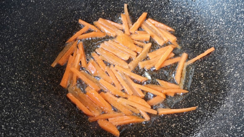 鸡蛋炒乌冬面,锅里继续倒油烧热,下入胡萝卜丝翻炒均匀。