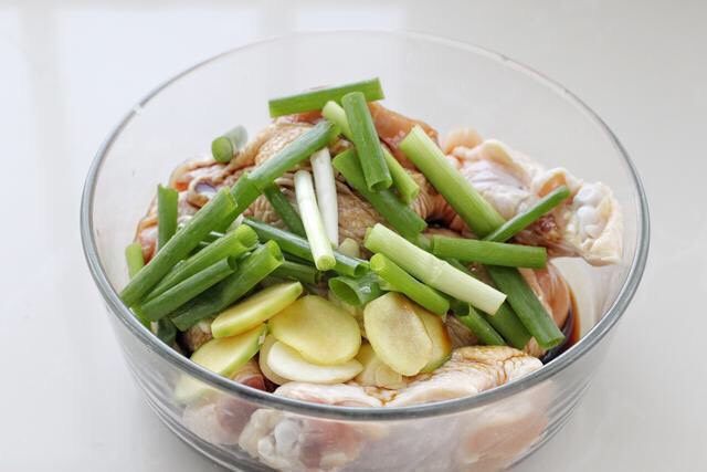 电饭锅焖鸡腿,将调好的酱汁倒入鸡腿中,再放入葱段、姜片和蒜片。