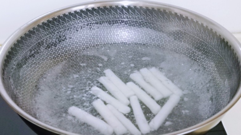 鱿鱼炒年糕,年糕洗干净后倒入锅中,水量没过年糕为佳,烧开煮2,煮好的年糕捞出放冷水中浸泡,这样使年糕更有韧性,口感更好。