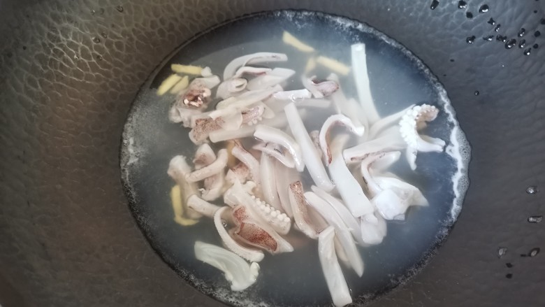 鱿鱼炒年糕,锅里水烧开倒入姜丝,倒入鱿鱼焯水半分钟捞出
