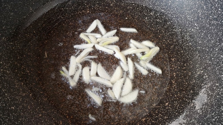 青椒炒豆皮,炒锅内倒适量的食用油烧热,下入蒜片炒香。