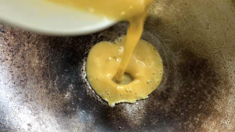 秋葵炒鸡蛋,中小火加入油烧热,并将蛋液加入其中。