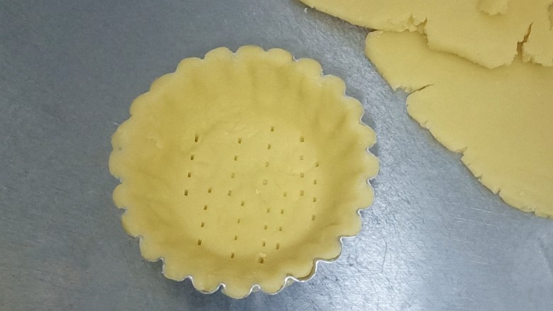 蓝莓派,取一个蛋挞模具或者派模具都可以。把面片平铺在模具上,贴着模具,小心的把面片按压贴合进去。再用叉子在底部戳几下,刷一层蛋液。如图。