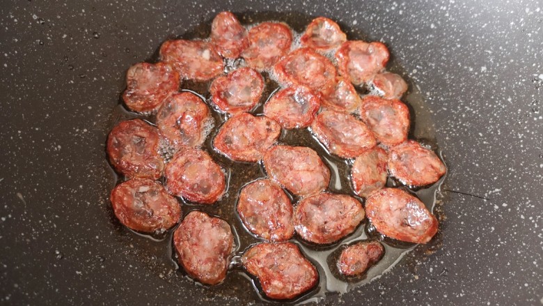 萝卜干炒肉,炒锅内倒适量的食用油烧热,下入腊肠煎至边缘卷曲,盛出备用。
