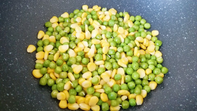 什锦玉米粒,炒锅内倒适量的食用油烧热,下入焯过的豌豆和玉米粒翻炒均匀。