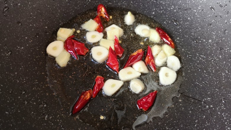 菌菇烩丸子,炒锅内倒适量的食用油烧热,下入大蒜、生姜和干红辣椒炒香。