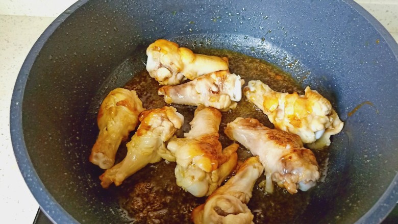 蒜香鸡腿,中小火慢慢熬至冰糖融化,加入鸡腿快速翻炒上色,加蒜泥炒香。