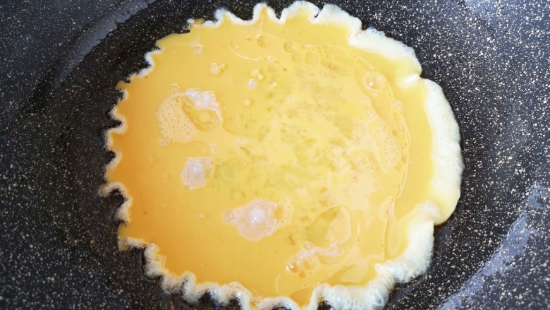 尖椒炒鸡蛋,炒锅内倒适量的食用油烧热,倒入蛋液。