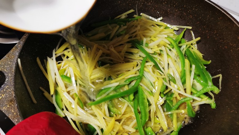 青椒炒土豆丝,加入少许水,以免糊锅