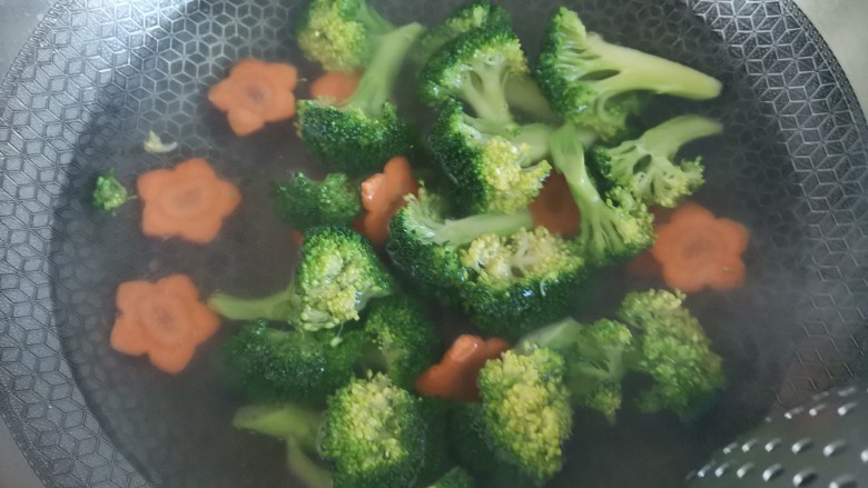 蒜蓉西兰花,水开下入西兰花和胡萝卜焯水一分钟,捞出控干水分