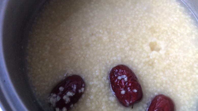 鸡蛋小米粥,把炖好的小米粥倒入另一个小锅里,加入红枣继续煮。