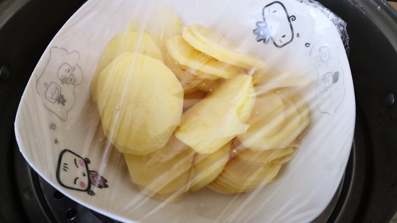 芝士土豆球,放在碗里,盖上保鲜膜,用牙签扎几个小孔,放在蒸锅里