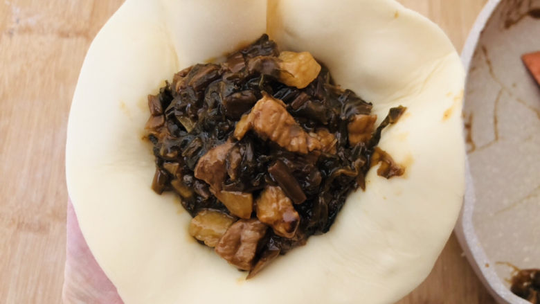 梅干菜肉包,放上调好的馅料,包成包子的形状。