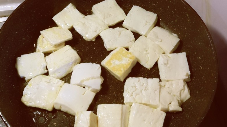 卤豆干,平底锅放入食用油加热,豆腐切块,放入锅中煎制。