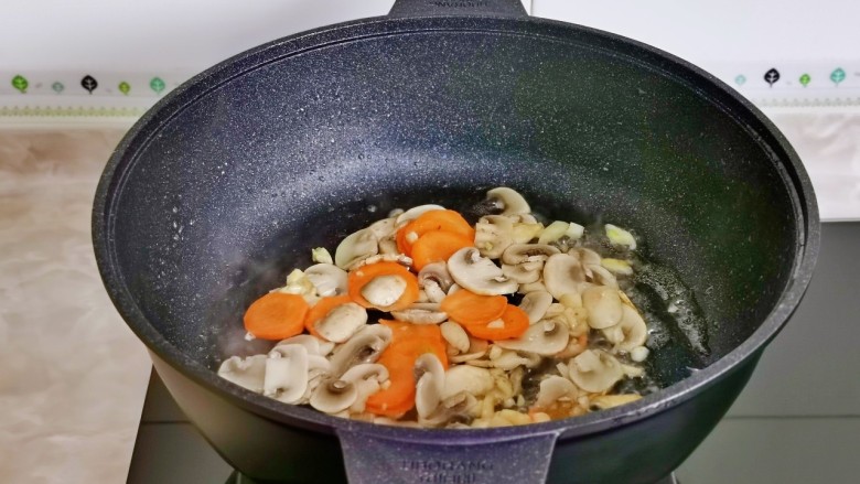 炒口蘑,加入蒜末炒香,加口蘑与胡萝卜片翻炒。