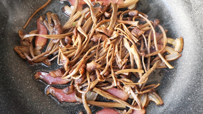 干锅茶树菇,加入茶树菇一起翻炒,让茶树菇沾满腊肉的香气后盛出。