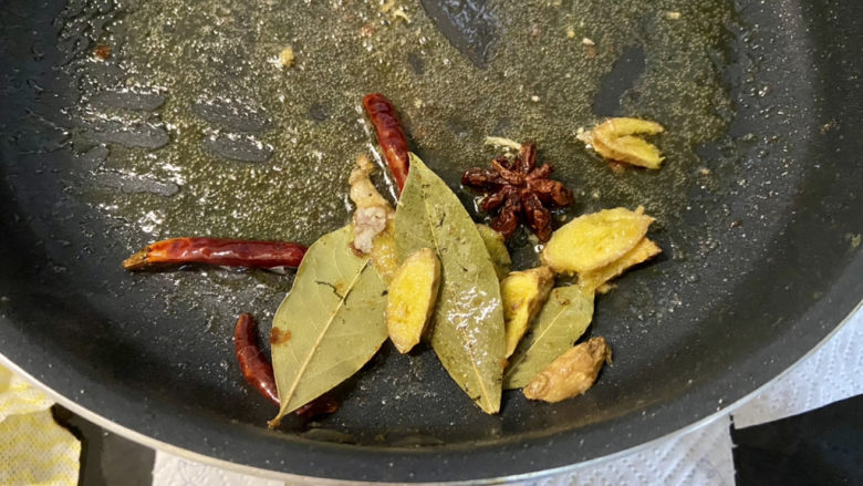 啤酒鸡翅根,锅中留底油,加入姜片干辣椒八角香叶,小火煸香