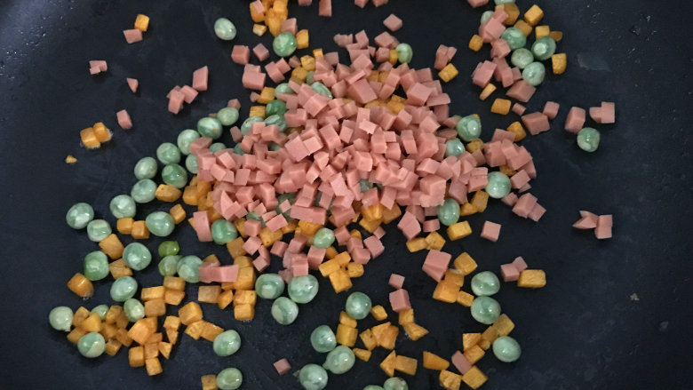 午餐肉饭团,用锅中余油,把豌豆和胡萝卜炒熟,再放入火腿炒出香味,盛出