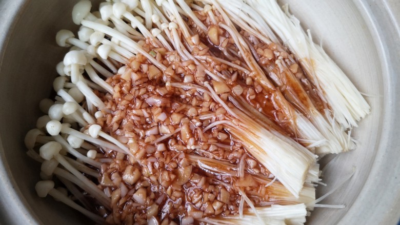 虾仁日本豆腐,将洗净的金针菇铺在砂锅底部,将煮开的蒜末料汁浇在金针菇上。