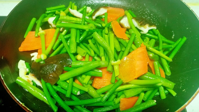 蒜台、豆角 、胡萝卜、 香菇炒鸡蛋,锅中放入少量油, 放入蒜拌炒香, 放入焯过水的蔬菜