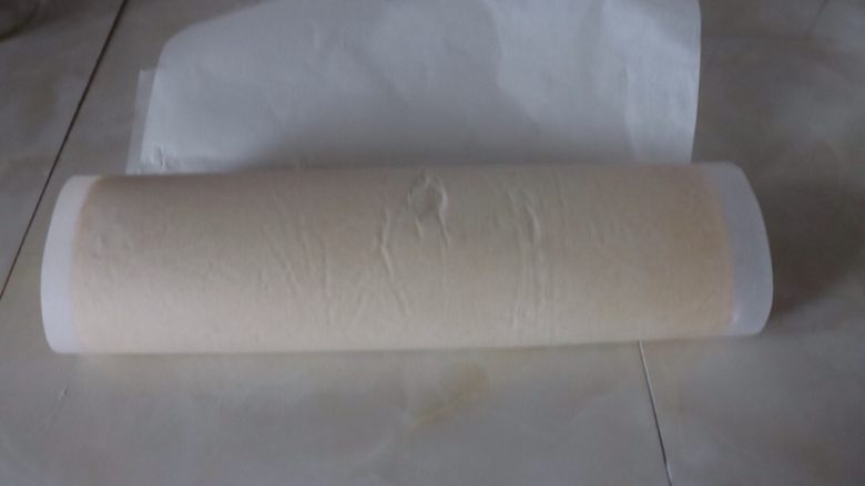 草莓香草奶油蛋糕卷,用油纸把蛋糕卷卷起来,油纸卷入蛋糕卷收口下面辅助蛋糕卷塑形,放入冰箱冷藏半小时^o^