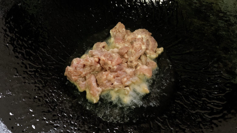 青椒炒牛肉,锅烧热油达到7/8成热后,转小火加入其中,滑炒一下(不用全熟透,一会儿要回锅再炒)