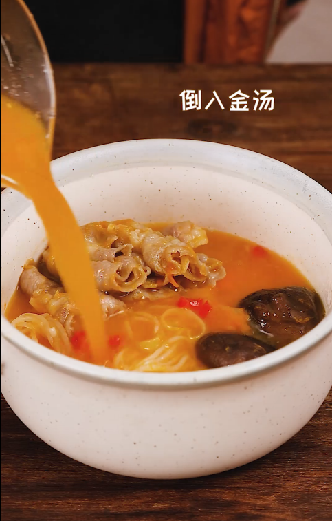 酸汤肥牛,将煮好的魔芋丝、金针菇、萝卜、香菇和肥牛摆在碗里,倒入金汤