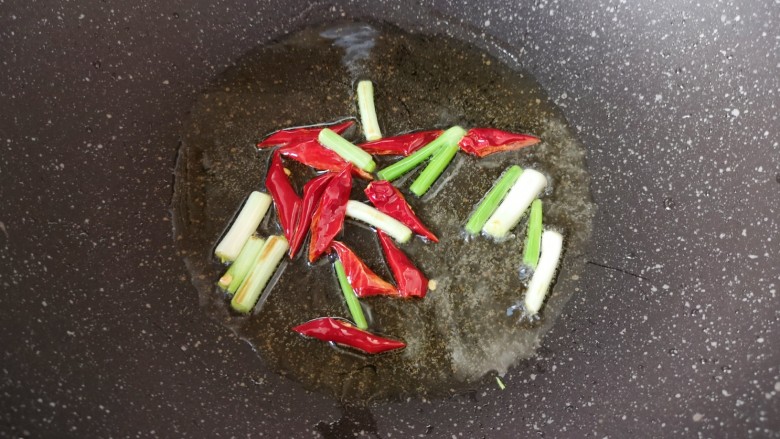 爆炒黄豆芽,炒锅内倒适量的食用油烧热,下入小葱和干红辣椒炒香。