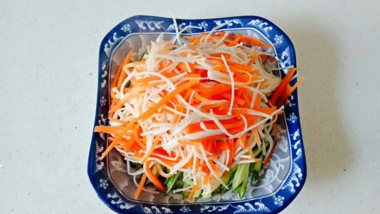 黄瓜凉拌金针菇,焯水后的金针菇和胡萝卜丝沥干水份,放入装黄瓜丝的盘中