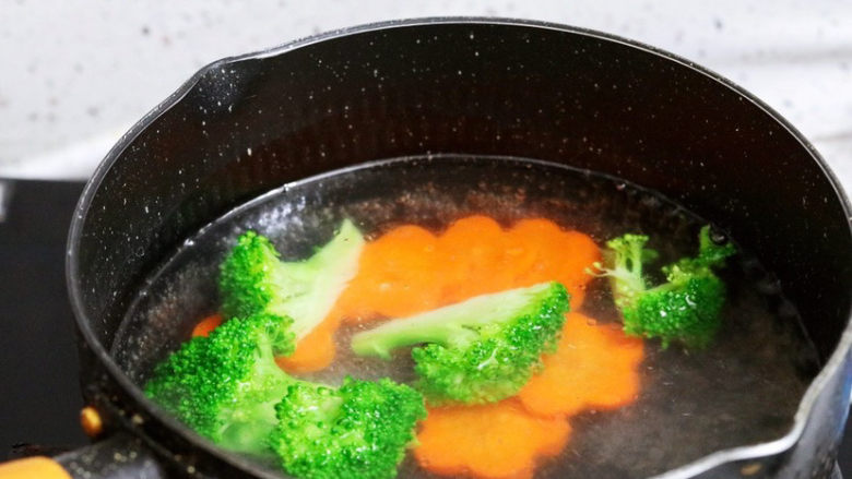 香煎龙利鱼,锅中注入清水烧开,加入1勺食用油和少许盐,再放入西兰花和胡萝卜,焯熟后捞出控干水分装入盘中备用