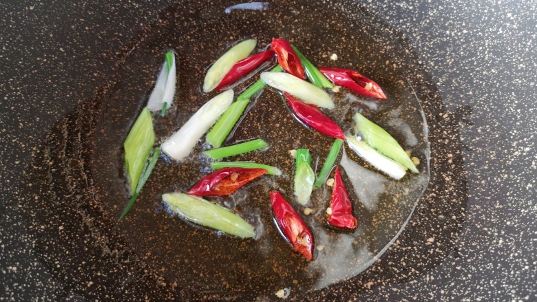 芹菜炒豆干,炒锅内倒适量的食用油烧热,下入小葱和干红辣椒炒香。