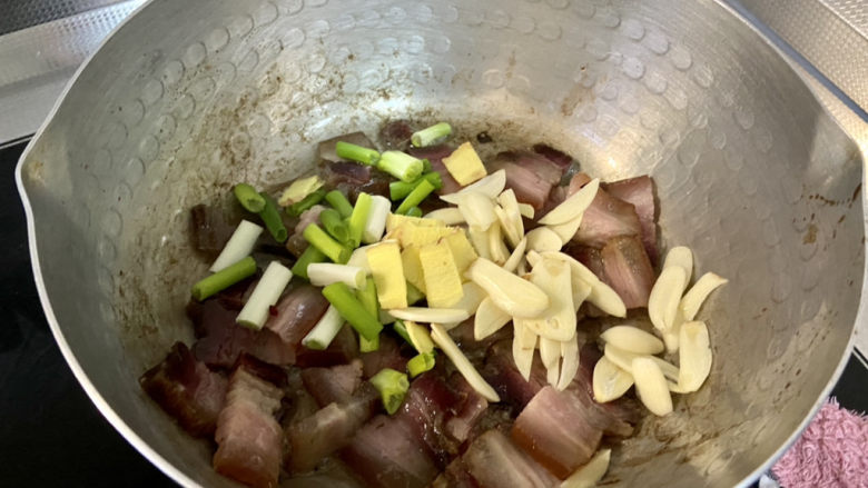 酸豆角炒腊肉,加入葱段姜片蒜片,中小火煸香