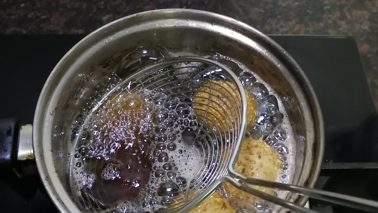 炸麻团,慢火炸至麻团浮上来,用笊篱轻轻压扁,待麻团再次浮上来,再轻轻压扁,如此反复几次以后,麻团变大了,而且炸出来是空心的,炸至表皮稍硬,并呈金黄色