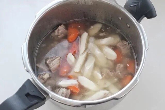 清炖羊肉,将高压锅从炉火上移下来泄压后打开锅盖,把葱、姜捞出丢弃不用,放入山药和胡萝卜盖好锅盖继续大火炖至上汽改小火炖五分钟。