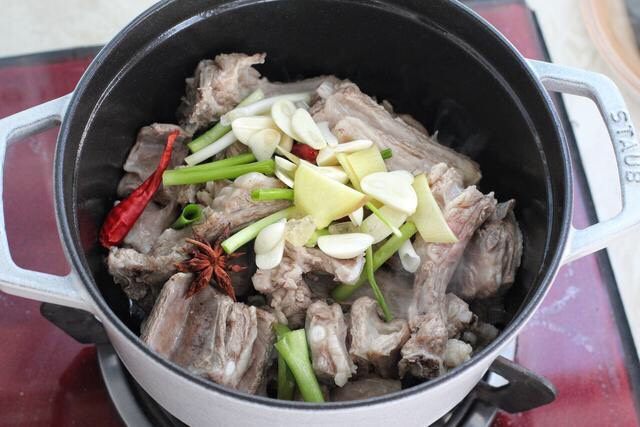 红烧羊肉,锅中倒入适量食用油烧热,下入羊排翻炒变色,接着放入葱白、姜蒜片、八角、陈皮、红干椒和冰糖,翻炒出香味儿。