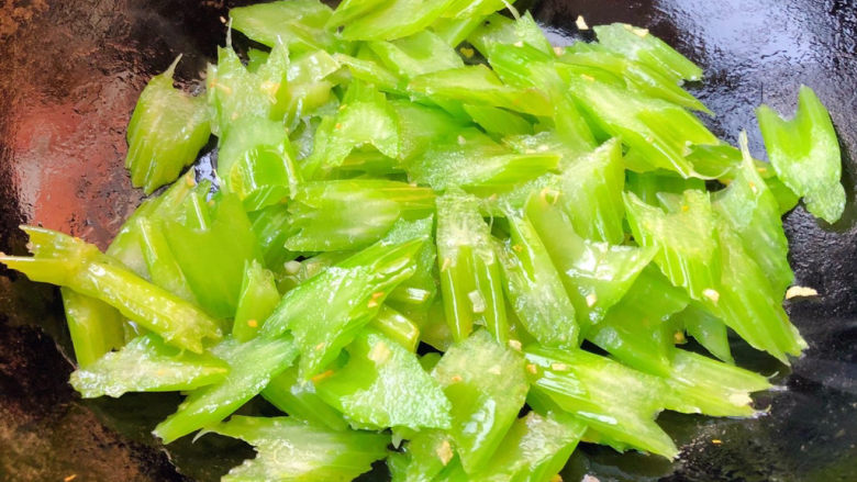 芹菜炒虾仁,锅中倒入底油加热放入蒜粒爆香再放入芹菜大火快速翻炒