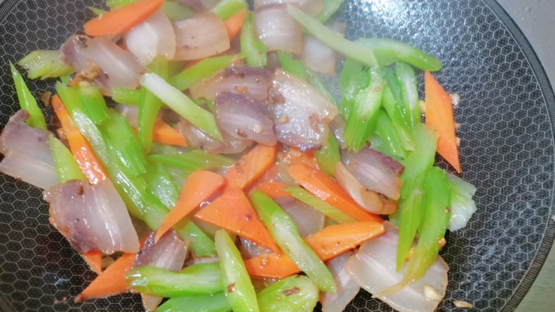 芹菜炒腊肉,炒至出油后,放入芹菜,胡萝卜,加入食用盐翻炒均匀